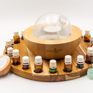 Könnte beinhalten: Ein Holz-Diffusor für ätherische Öle mit einer Glaskuppel und einem drehbaren Tablett, das 16 Flaschen mit ätherischen Ölen aufnehmen kann. Der Diffusor ist mit "Young Living Essential Oils" beschriftet.