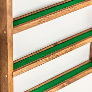 May include: A wooden wall shelf with three shelves lined with green felt. The shelf is made of dark wood and has brass accents.