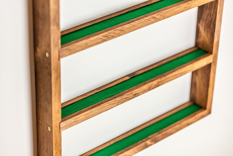 May include: A wooden wall shelf with three shelves lined with green felt. The shelf is made of dark wood and has brass accents.