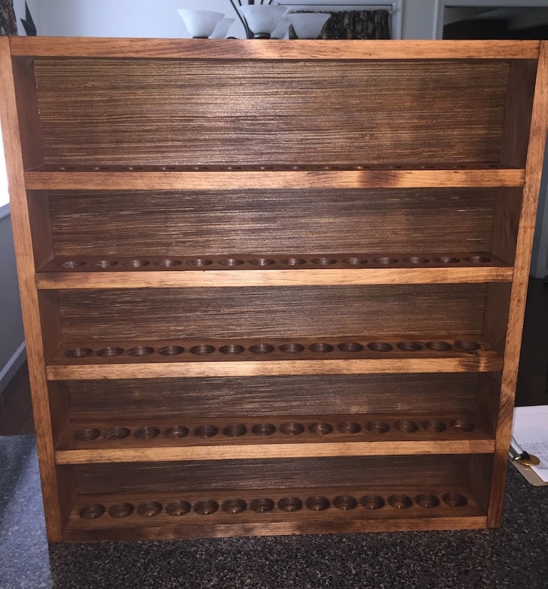 May include: A wooden shelf unit with five shelves, each with multiple circular holes. The shelves are stained a dark brown color.