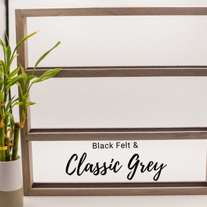 May include: A three-tiered wooden shelf with black felt lining. The shelf is labeled "Black Felt & Classic Grey".
