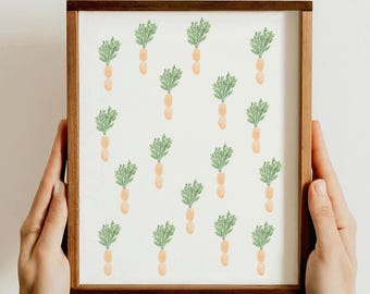 May include: A framed print featuring a repeating pattern of watercolor carrots. Each carrot has a light orange body and green leafy top. The wooden frame has a dark brown finish. The print is held by two hands.