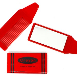 May include: Red plastic comb and mirror set shaped like a crayon. The packaging reads "Crayon Comb & Mirror Set".
