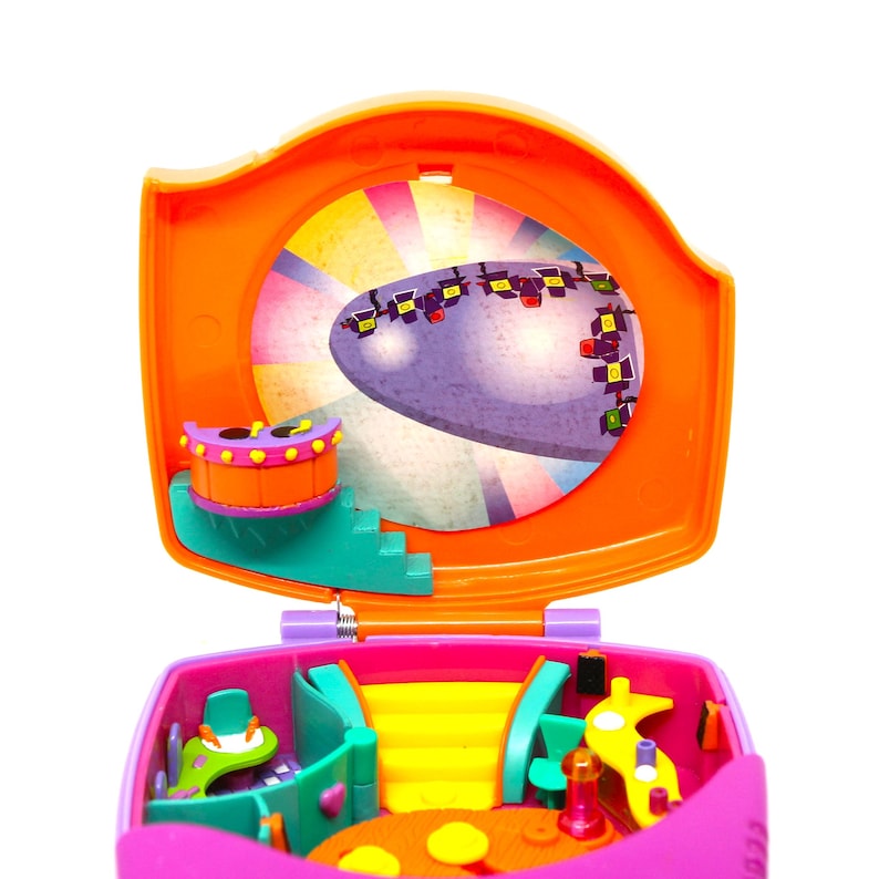 Puede incluir: Un juego de juguetes de pl&aacute;stico rosa y naranja con un escenario y una rueda giratoria. El escenario tiene un fondo morado con un dise&ntilde;o de arco&iacute;ris. La rueda giratoria tiene un dise&ntilde;o de arco&iacute;ris y un centro morado.