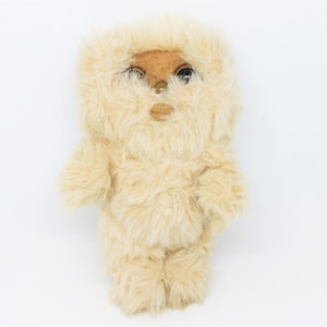 Peut inclure: Un jouet en peluche ressemblant à un Wookiee de Star Wars. Le jouet est brun clair avec une texture pelucheuse et a des yeux noirs.