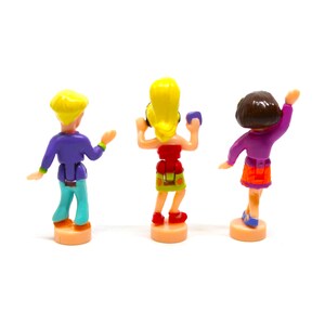 Puede incluir: Tres figuritas de pl&aacute;stico de personas bailando. Las figuras llevan ropa colorida y est&aacute;n posadas de forma din&aacute;mica. Las figuras est&aacute;n sobre un fondo blanco.