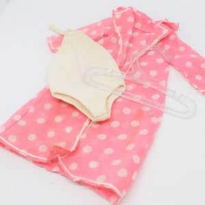May include: A pink polka dot dressing gown with white trim and a white swimsuit.