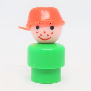 May include: A green and orange plastic toy figure with a smiling face and a red hat. The figure is a classic toy for children.