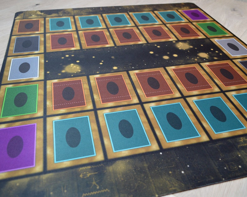 Puede incluir: Un tablero de juego con fondo negro y detalles dorados. El tablero tiene 25 casillas, cada una con un borde de color diferente y un c&iacute;rculo negro en el centro. Las casillas est&aacute;n dispuestas en una cuadr&iacute;cula de 5x5.