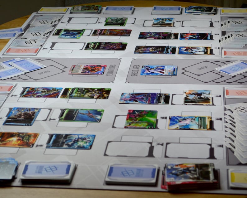 May include: A tabletop card game setup with a gray playmat featuring designated areas. Various colorful trading cards are arranged on the mat, along with stacks of cards and card holders. The cards display vibrant illustrations.