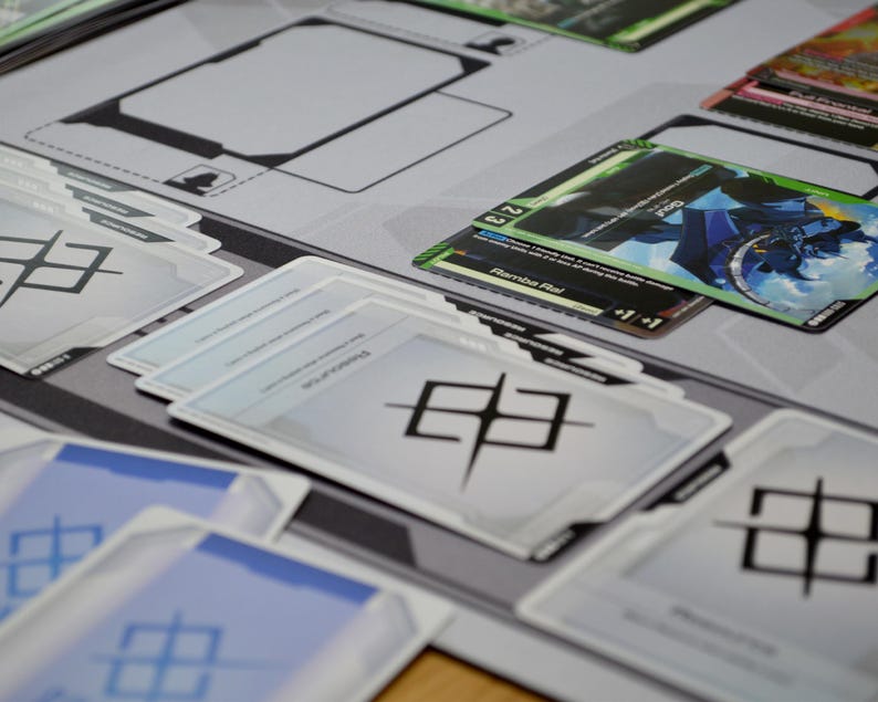 May include: A close-up of a tabletop game setup featuring various cards and a playmat. The cards have colorful illustrations and text, with a dominant color scheme of blue, green, and white. The playmat is gray with black outlines.