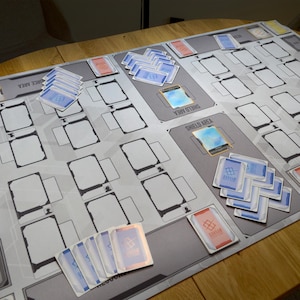 May include: A white ceramic mug with a black handle and the text "But First, Coffee" in a black, handwritten-style font. The mug is on a white surface.