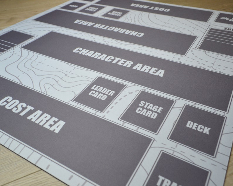 K&ouml;nnte beinhalten: Eine grau-wei&szlig;e Spielmatte mit beschrifteten Bereichen f&uuml;r das Gameplay. Die Matte enth&auml;lt Text wie "Character Area", "Cost Area" und "Deck". Das Design umfasst ein karten&auml;hnliches Muster mit Konturlinien und gestrichelten Linien.