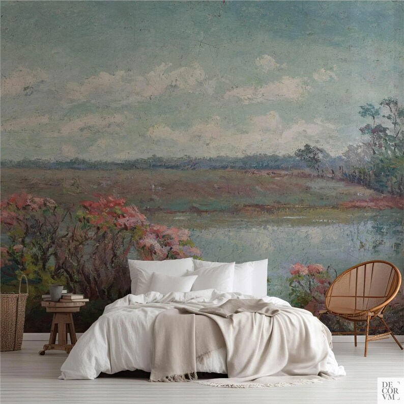 May include: Bedroom with a landscape mural featuring a serene lake scene with pink flowering bushes. The bed has white bedding and a beige throw blanket. A wooden side table with books and a woven basket are visible.