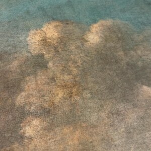 May include: A close-up of a textured fabric with a faded, watercolor-like design of clouds in shades of blue, brown, and white.