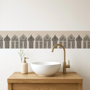 May include: A bathroom interior with a wooden vanity, a white circular sink, and a gold tap. A beige soap dispenser and a decorative border with a repeating geometric design are also present. The style is clean and modern, with a neutral colour palette.