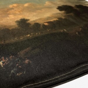 May include: A black pillow with a zipper closure. The front of the pillow features a printed image of a landscape painting with a cloudy sky and a group of people in the foreground.