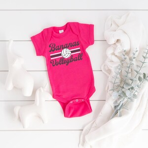 a baby bodysuit sitting next to a plant