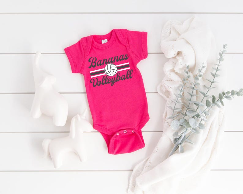 a baby bodysuit sitting next to a plant