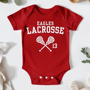 a baby bodysuit with a lacrosse design on it