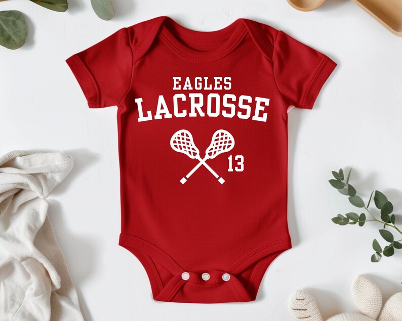 a baby bodysuit with a lacrosse design on it