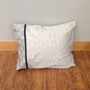 May include: A gray pillow with a white and green patterned design. The pillow has a black and gray trim.