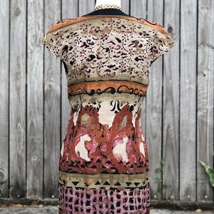 May include: A patterned dress with a scoop neckline and cap sleeves. The dress features a mix of colors, including beige, brown, and pink, with a floral and geometric design. The dress is displayed on a white mannequin.