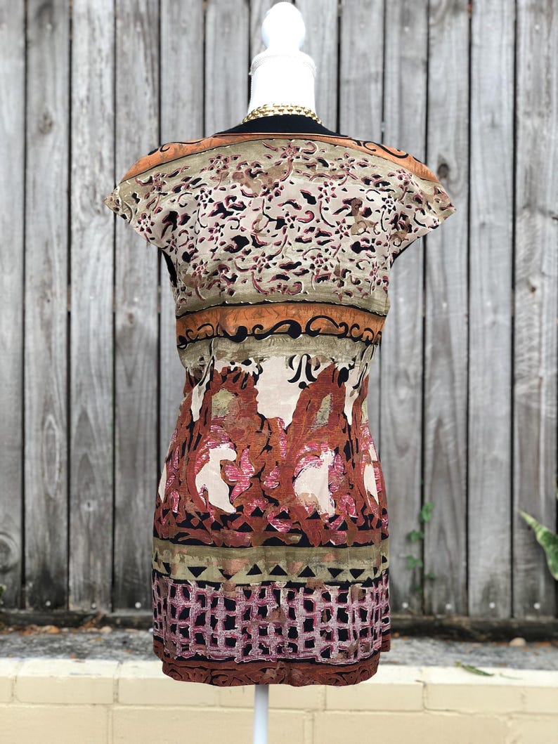 May include: A patterned dress with a scoop neckline and cap sleeves. The dress features a mix of colors, including beige, brown, and pink, with a floral and geometric design. The dress is displayed on a white mannequin.