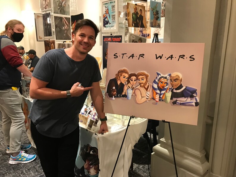 Peut inclure: Une illustration dessin&eacute;e &agrave; la main de personnages de Star Wars savourant des milkshakes. Les personnages sont dessin&eacute;s dans un style cartoon et portent leurs tenues embl&eacute;matiques. L'illustration est sur une toile et est expos&eacute;e sur un chevalet. Le texte "S.T.A.R. W.A.R.S." est &eacute;crit dans une police de caract&egrave;res stylis&eacute;e en haut de la toile.