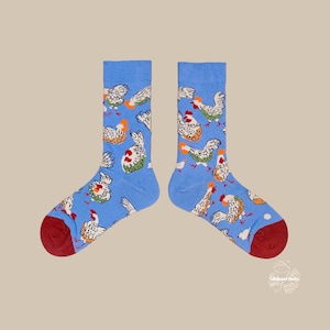 May include: A pair of blue socks with a repeating pattern of cartoon chickens in various colors. The socks have red heels and toes. The chickens are white, orange, and green.