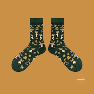 May include: A pair of green socks with a whimsical pattern of women in floral hats and dresses. The socks have a white background with yellow, pink, and blue accents.