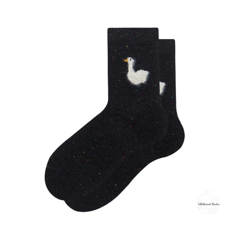 May include: A pair of black fuzzy socks with a white goose design. The goose has a yellow beak and is embroidered on the socks.