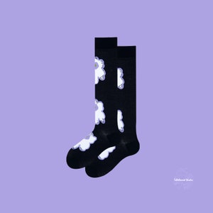 May include: A pair of black knee-high socks with a white floral pattern. The socks are made of a soft, comfortable material and are perfect for everyday wear.