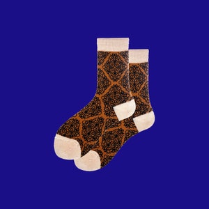 May include: A pair of brown socks with a black geometric pattern. The socks are folded and have a white cuff.