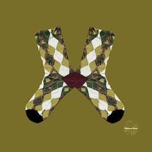 Puede incluir: Un par de calcetines de rombos con un patrón de diamantes verdes, blancos y marrones. Los calcetines tienen punteras negras y un rombo burdeos en el centro. El fondo es verde oliva.