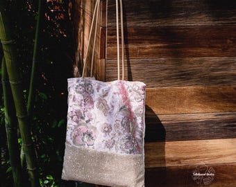 Peut inclure: Un sac fourre-tout rectangulaire composé d'une partie supérieure en velours rose avec une broderie florale complexe et d'une partie inférieure en tissu doré scintillant. Le sac possède deux longues anses fines en corde claire.