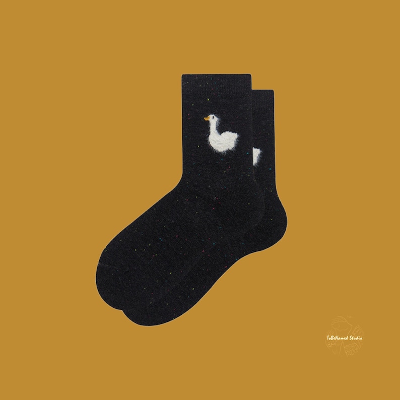 May include: A pair of black fuzzy socks with a white embroidered goose design.