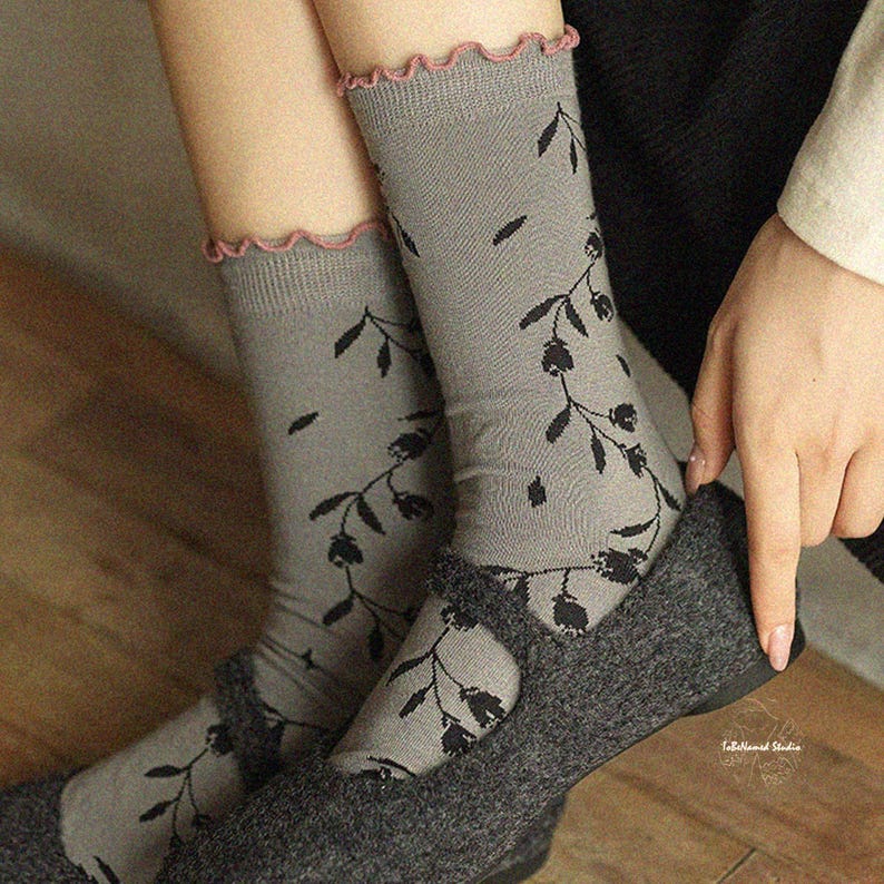 Side-angled view of the Wildflower Vine socks showing the elegant drape and delicate pink trim against a neutral background