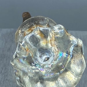 May include: A clear glass door knob with a faceted design. The knob has a silver screw in the center.