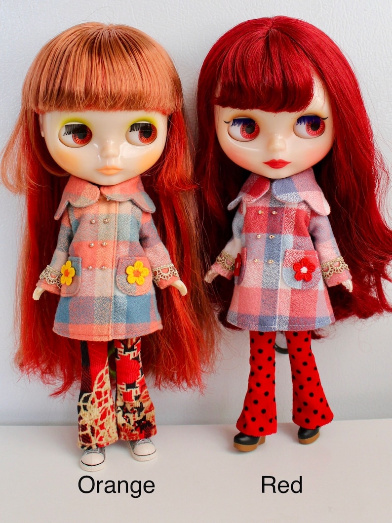 May include: Two dolls with long red hair wearing plaid coats and bell bottom pants. The doll on the left has orange hair and is wearing floral pants. The doll on the right has red hair and is wearing red and black polka dot pants. The dolls are labeled "Orange" and "Red".