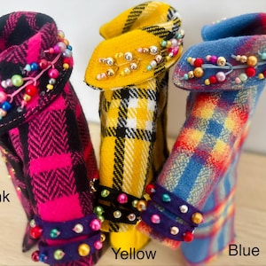 May include: Three miniature coats in pink, yellow, and blue plaid patterns. Each coat features a collar and cuffs embellished with colorful beads. The text Pink, Yellow, and Blue is printed below the respective coats to identify each color variant.