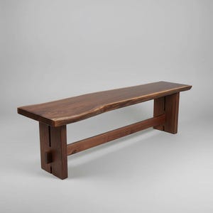 May include: A dark brown wooden bench featuring a live edge seat with a natural wood grain pattern. The bench is supported by two vertical slab legs connected by a horizontal stretcher bar, showcasing a clean, structural design with visible joinery.
