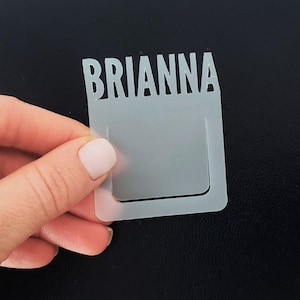 May include: White plastic bookmark with the name "BRIANNA" printed in a bold, sans-serif font. The bookmark has a rectangular shape with a small rectangular cutout at the top.