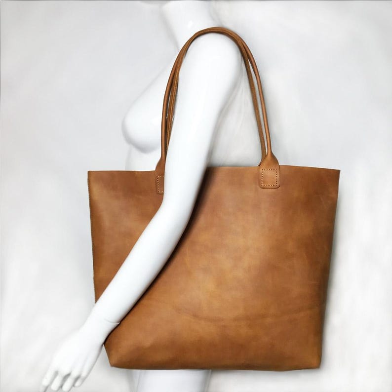 May include: A large brown leather tote bag with two handles. The bag is made from soft, supple leather and has a spacious interior.