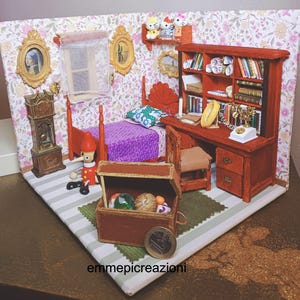 Könnte beinhalten: Miniatur-Schlafzimmer-Diorama mit rotem Bett, Schreibtisch und Bücherregal. Die Szene umfasst eine Pinocchio-Figur, eine Schatzkiste und gerahmte Kunstwerke. Die Wände sind mit floraler Tapete verziert, und der Boden hat einen gestreiften Teppich.