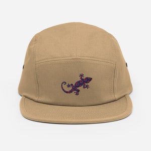 Könnte beinhalten: Eine beige 5-Panel-Kappe mit einem gestickten blauen und roten Gecko auf der Vorderseite.