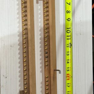 May include: Wooden strips with brass studs and metal hooks. A yellow tape measure shows the longest strip is approximately 23 inches long. The items are on a white surface.