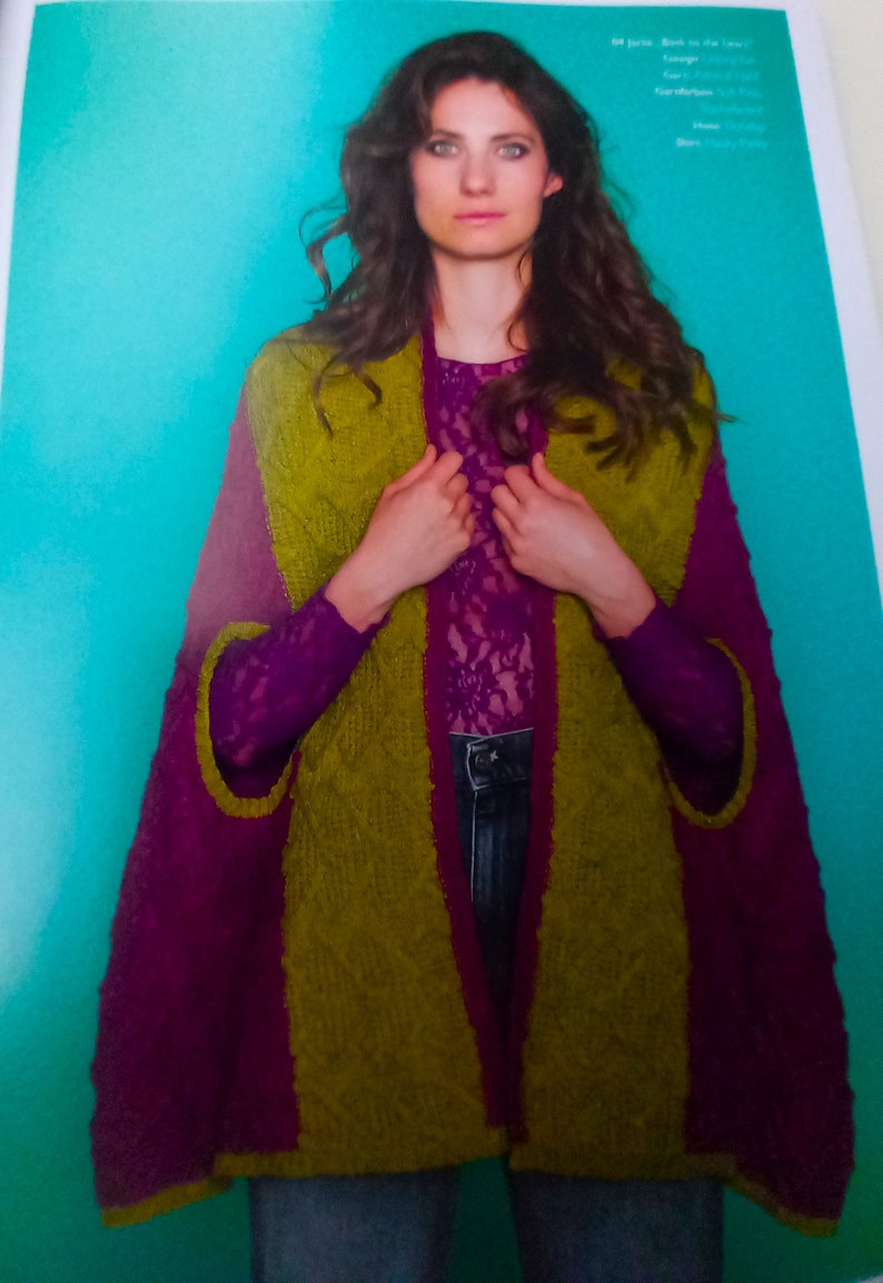 May include: A green and purple knitted cardigan with a shawl collar. The cardigan is open in the front and the model is wearing it over a lace top.
