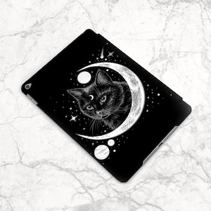 May include: Black and white illustration of a cat with a third eye, sitting inside a crescent moon with stars and planets. The design is on a black background.