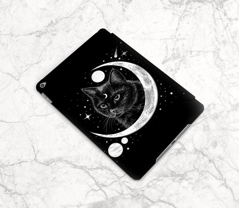 May include: Black and white illustration of a cat with a third eye, sitting inside a crescent moon with stars and planets. The design is on a black background.